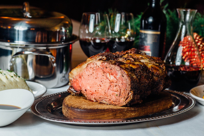 Roast prime rib on a platter with glasses of wine